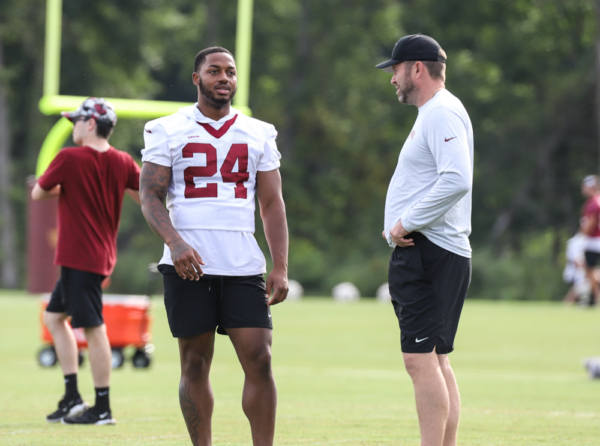 RB Antonio Gibson (24) chats with a coach before practice Comman
