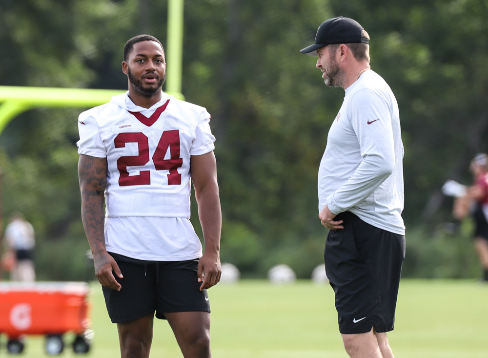 RB Antonio Gibson (24) chats with a coach before practice Comman