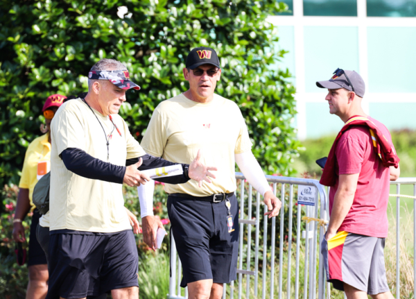Washington Commanders Head Coach Ron Rivera speaks to another co