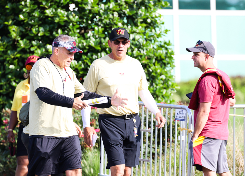 Washington Commanders Head Coach Ron Rivera speaks to another co